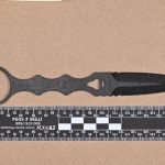 Evidence photo: the fixed-blade dagger with forensic ruler from the Washington OII case report