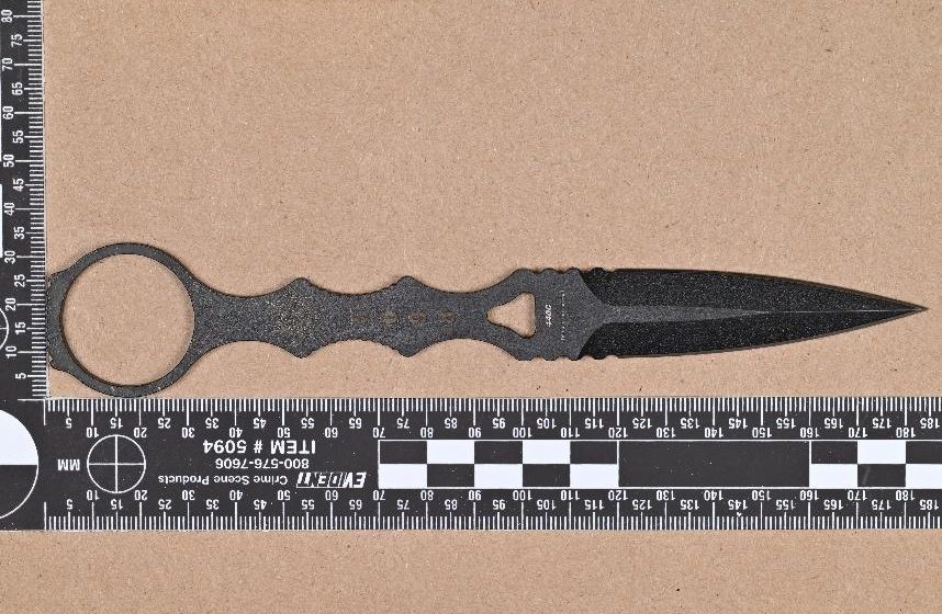 Evidence photo: the fixed-blade dagger with forensic ruler from the Washington OII case report